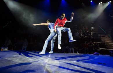 Two male actors from Memoirs of An Asian Football Casual triumphantly jumping in the air whilst facing back to back.