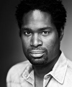 A black and white headshot of actor Ako Mitchell