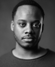 A black and white headshot of actor Simon-Anthony Rhoden