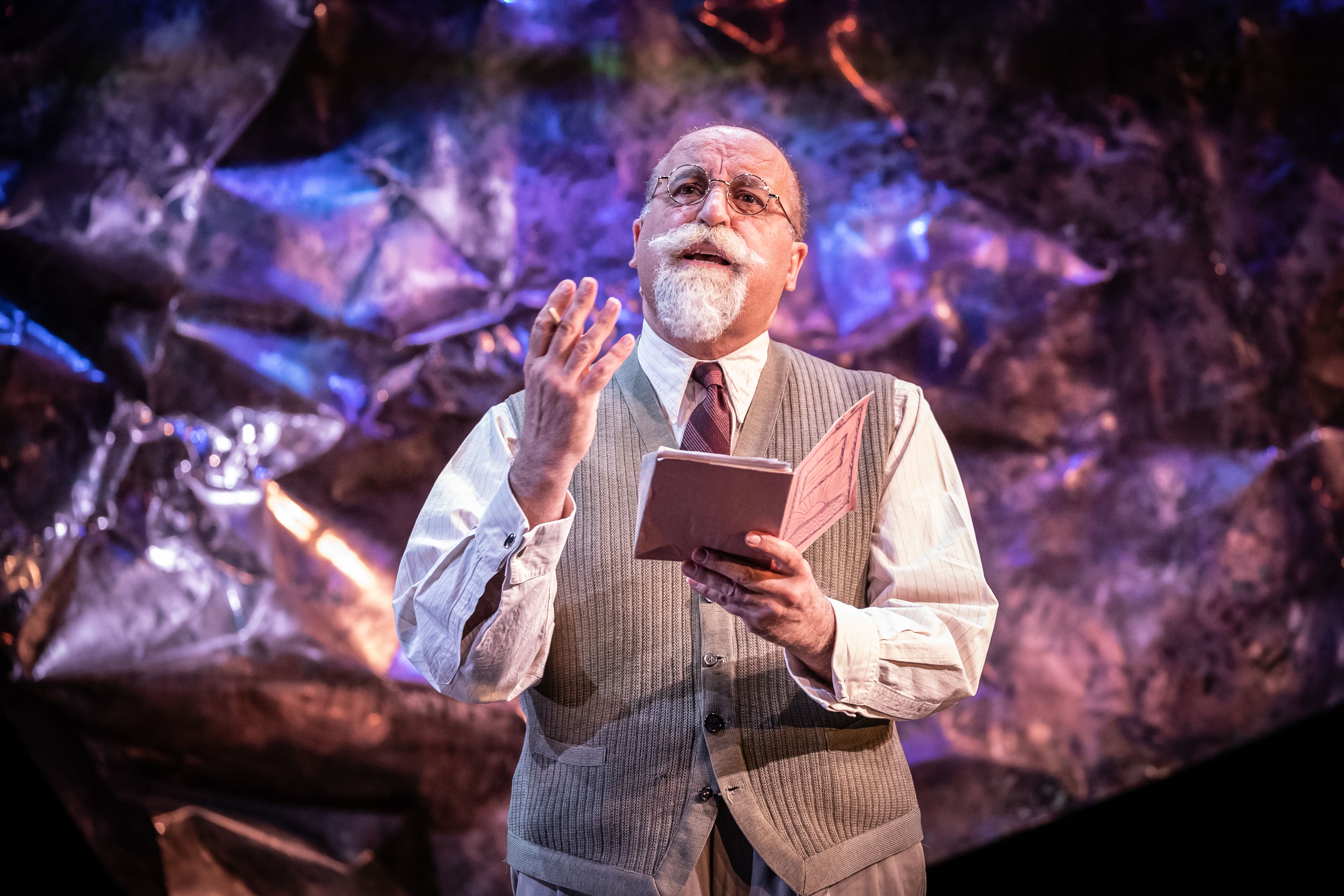 Male cast Member with white moustache speaking words of wisdom whilst holding his notebook