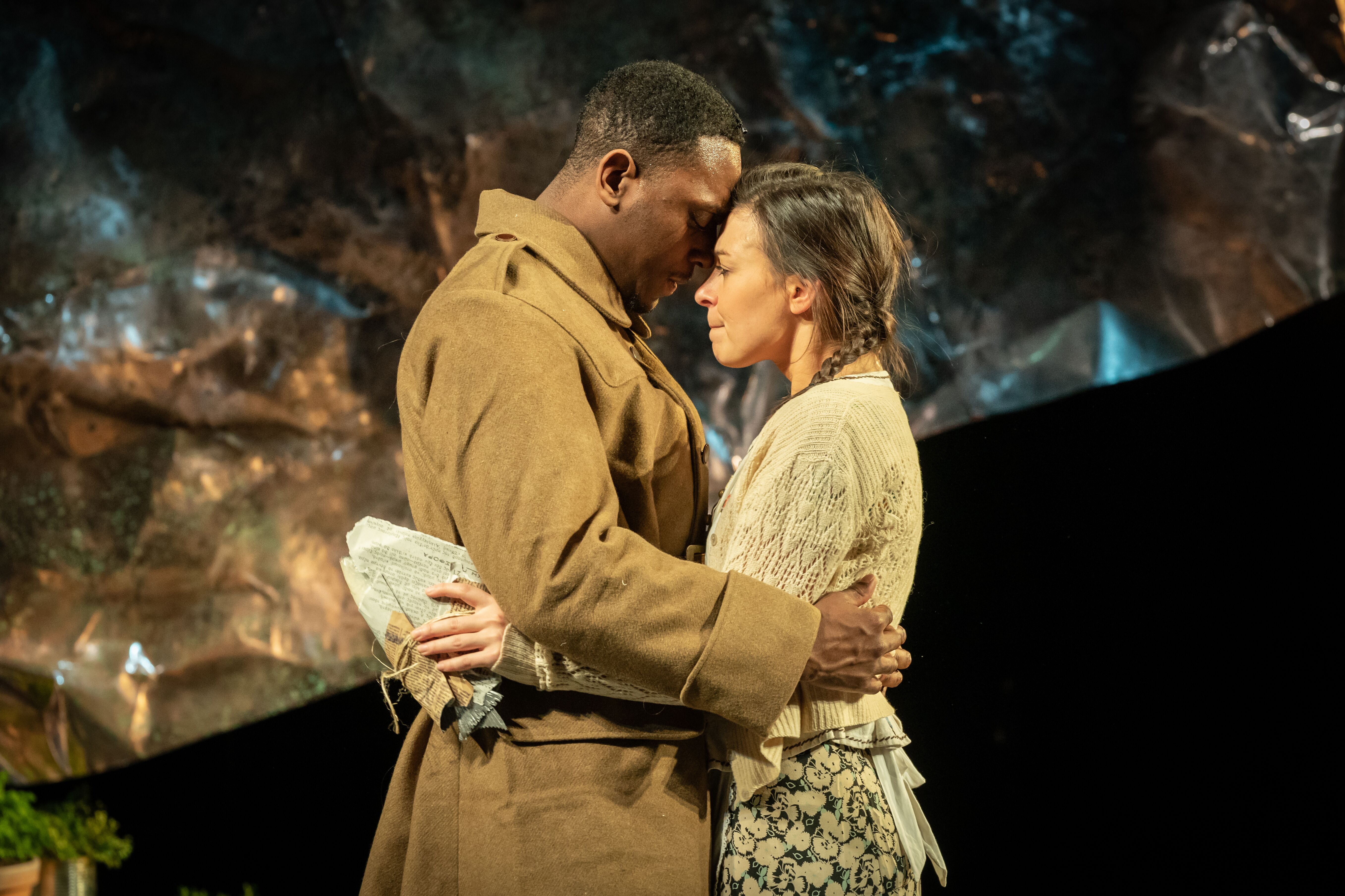 Soldier and lady standing facing each other with their foreheads pressed against one another with their arms wrapped around one another