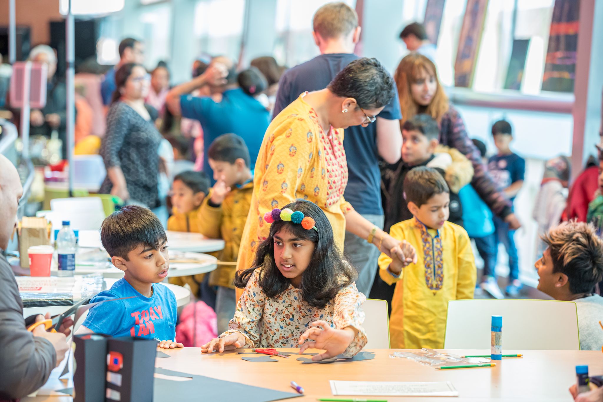 Children and their adults participating in a drop-in craft workshop.