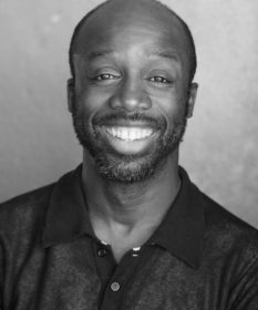 A black and white headshot of actor Jo Servi.