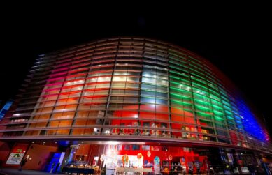 Exterior night-time image of Curve illuminated in rainbow lights.